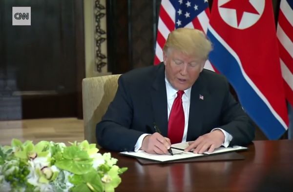 Дональд Трамп и Ким Чен Ын подписывают итоговый документ.